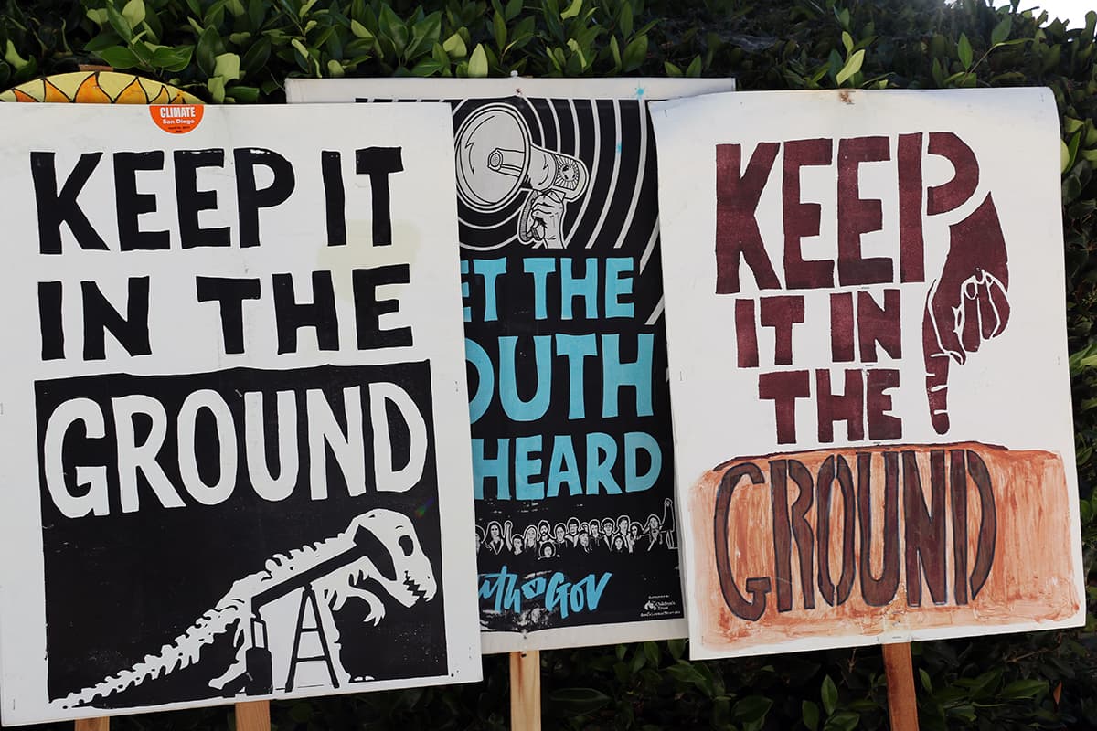 Photo of three Green New Deal supports smiling and holding signs