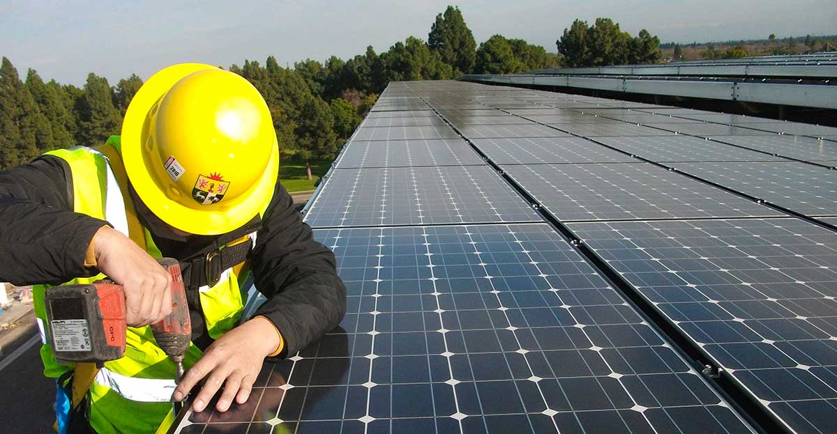 Electrician mounting solar panels atop roof